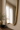 Close detail of Nerra's slim brass-toned frame and waved lower edge